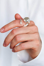 Hand wearing a silver AirPod ring with pearls on a white background